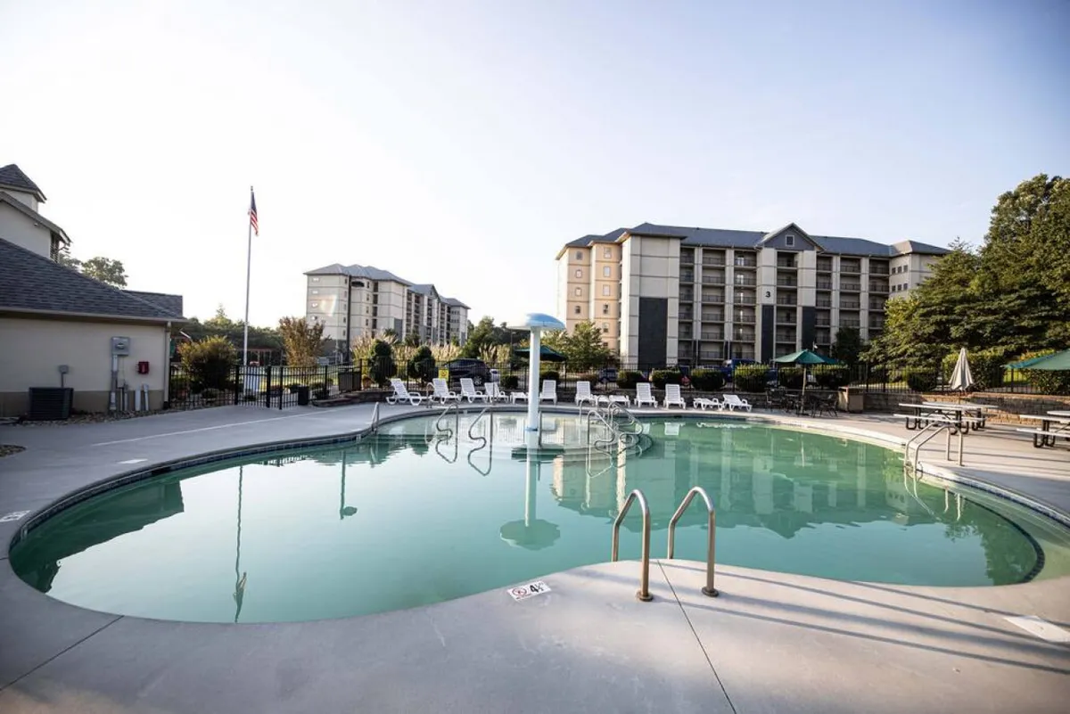 The resort's swimming pool is surrounded by lounge chairs and greenery with the building architecture in the background. The setting invites both social gatherings and quiet relaxation, highlighting the pool as a hub for group enjoyment.