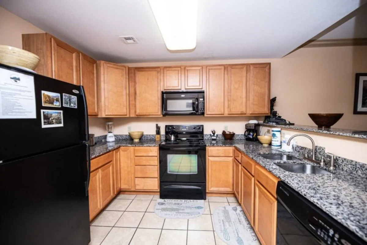 The kitchen is highlighted with granite countertops, black appliances, and warm wood cabinetry. The setup is ideal for preparing everything from quick snacks to full feasts, and the layout encourages social interaction during cooking.