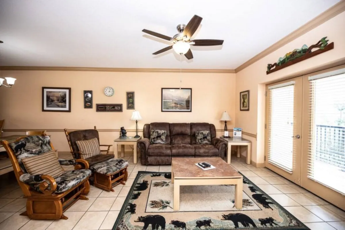 A cozy living room scene with a sofa, coffee table, and wooden rocking chairs. Decorative wall art and soft lighting create an inviting atmosphere. The arrangement is perfect for intimate conversations, playing board games, or unwinding after a day of adventure.