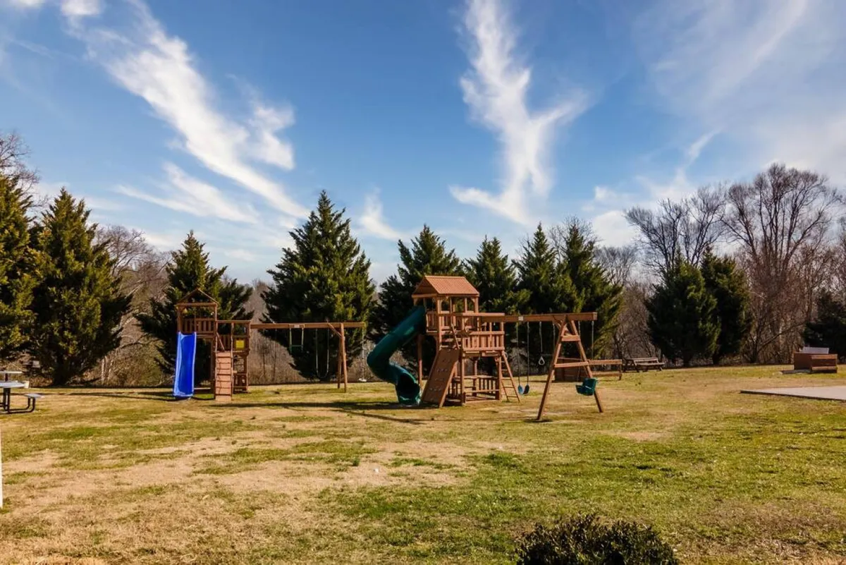 This playful exterior image focuses on the resort’s brightly colored playground equipment, including swings and a slide, surrounded by green grass. Families and children are enjoying the space, illustrating a joyful and safe environment for younger guests.